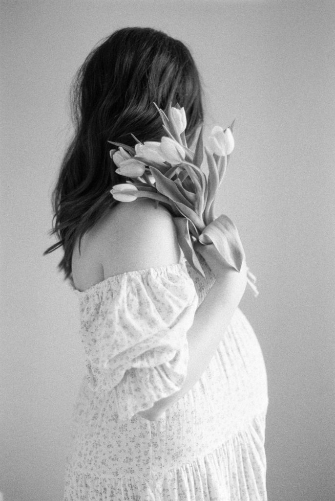 black and white film image of beautiful pregnant mother, holding tulips captured by Edmonton maternity photographer, Kahla Kristen Photography