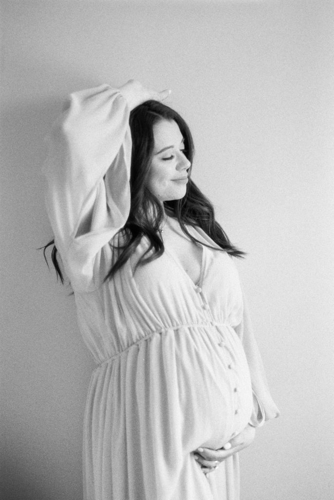 black and white image of expectant mother smiling captured by Edmonton maternity photographer, Kahla Kristen Photography
