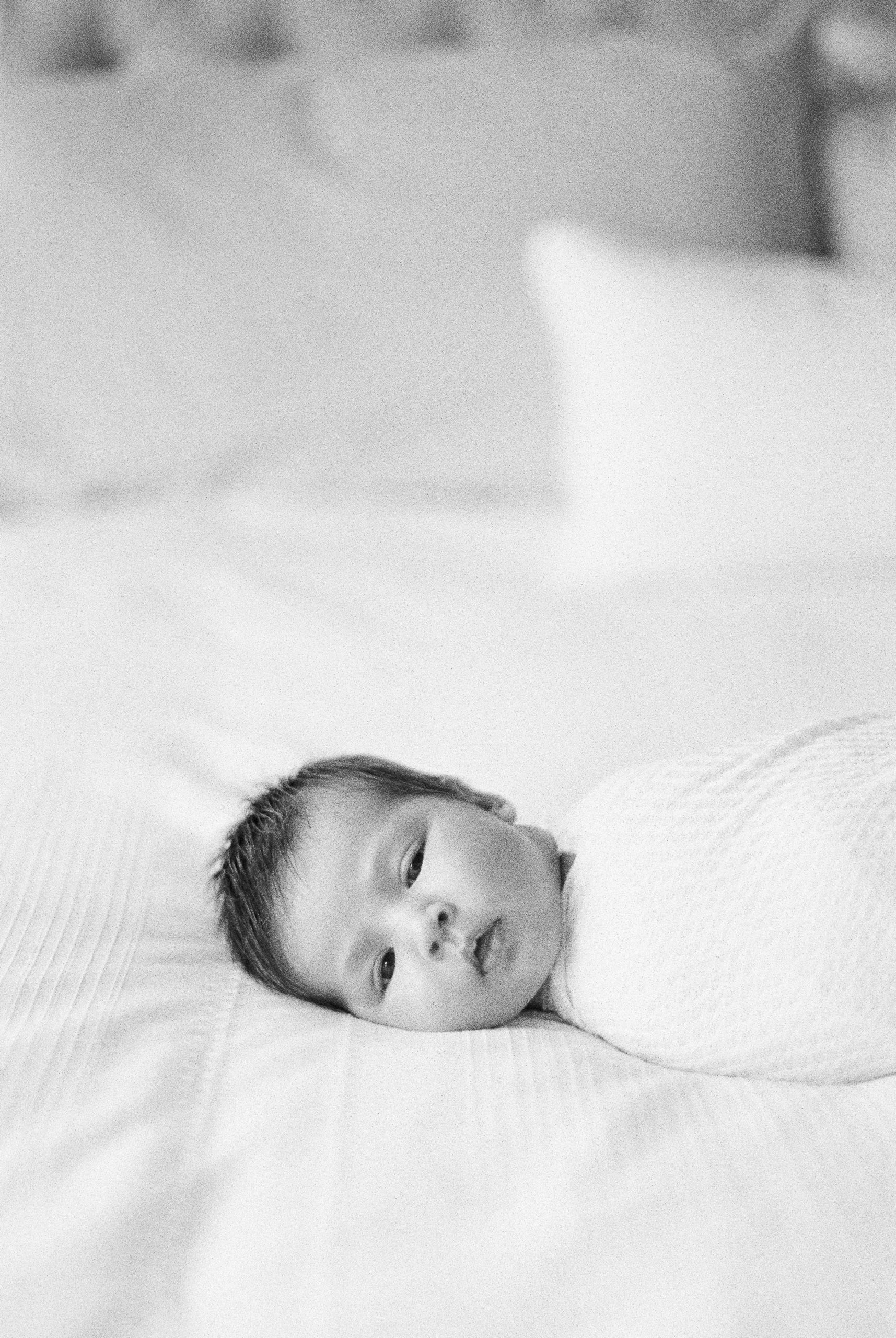 Newborn baby laying on bed looking at camera at Edmonton newborn photoshoot