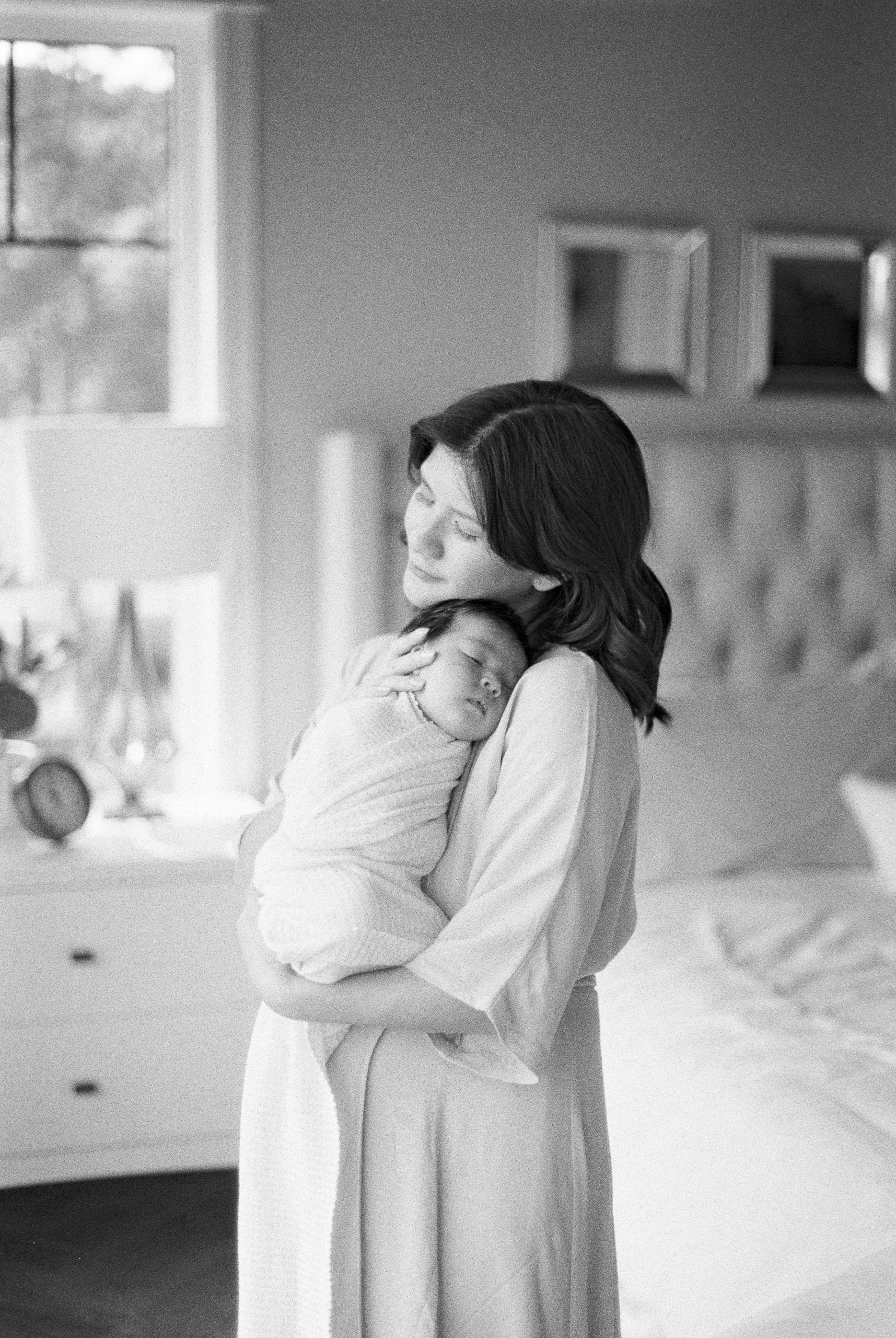 Mother holding newborn baby on chest in black and white film