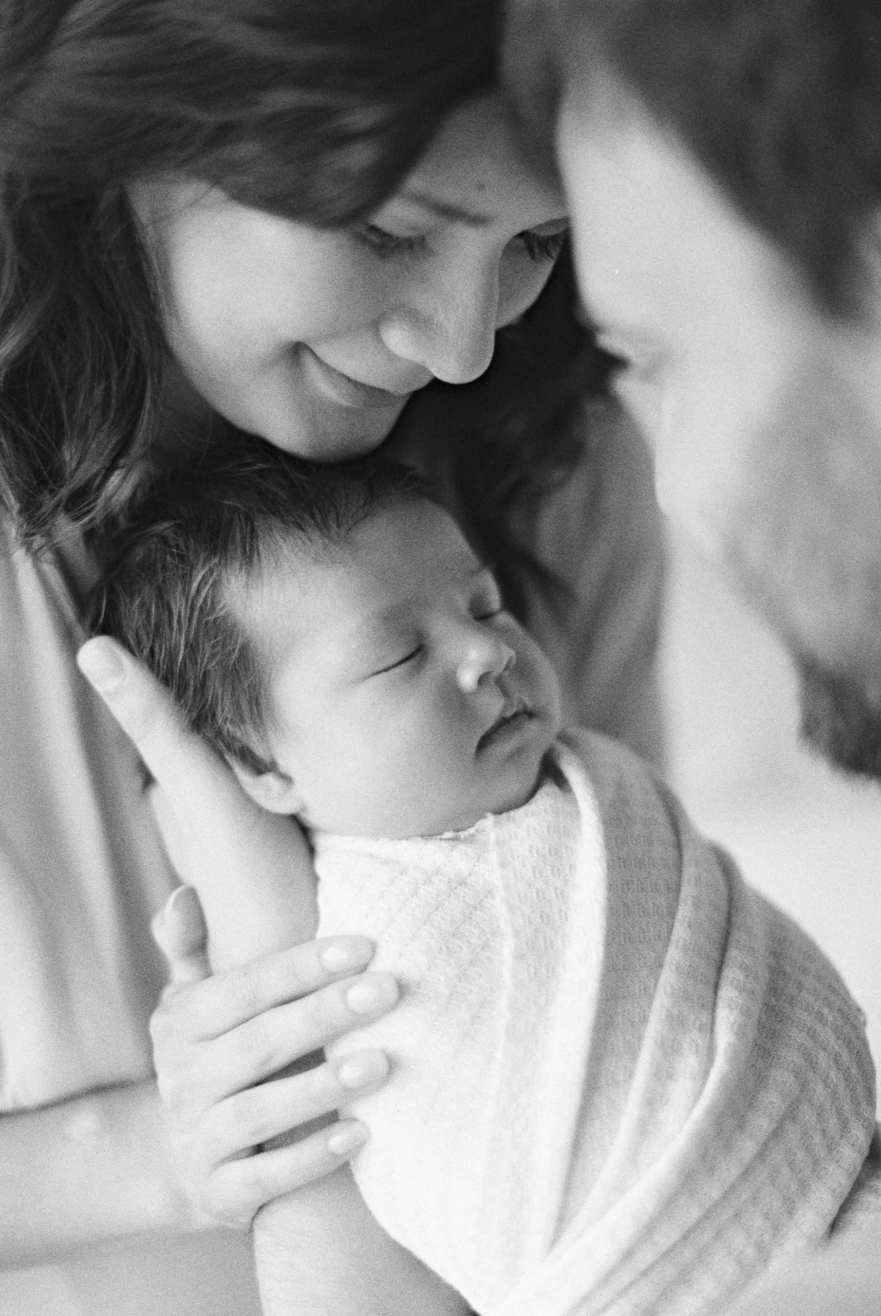 Close up of new family snuggling newborn baby in black and white