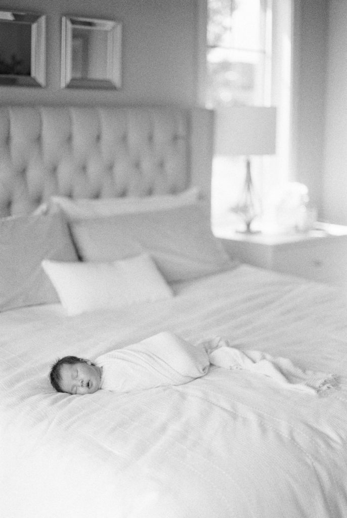 Newborn baby asleep on bed on black and white film