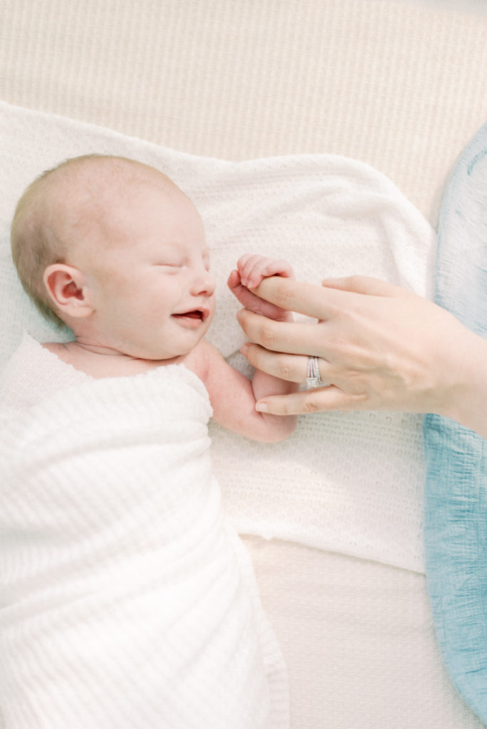 Newborn baby holding mom's finger