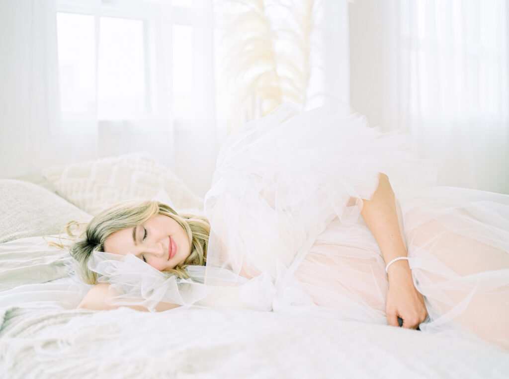 When to book a maternity shoot | Edmonton Maternity Photography, image of expectant mom laying on bed 