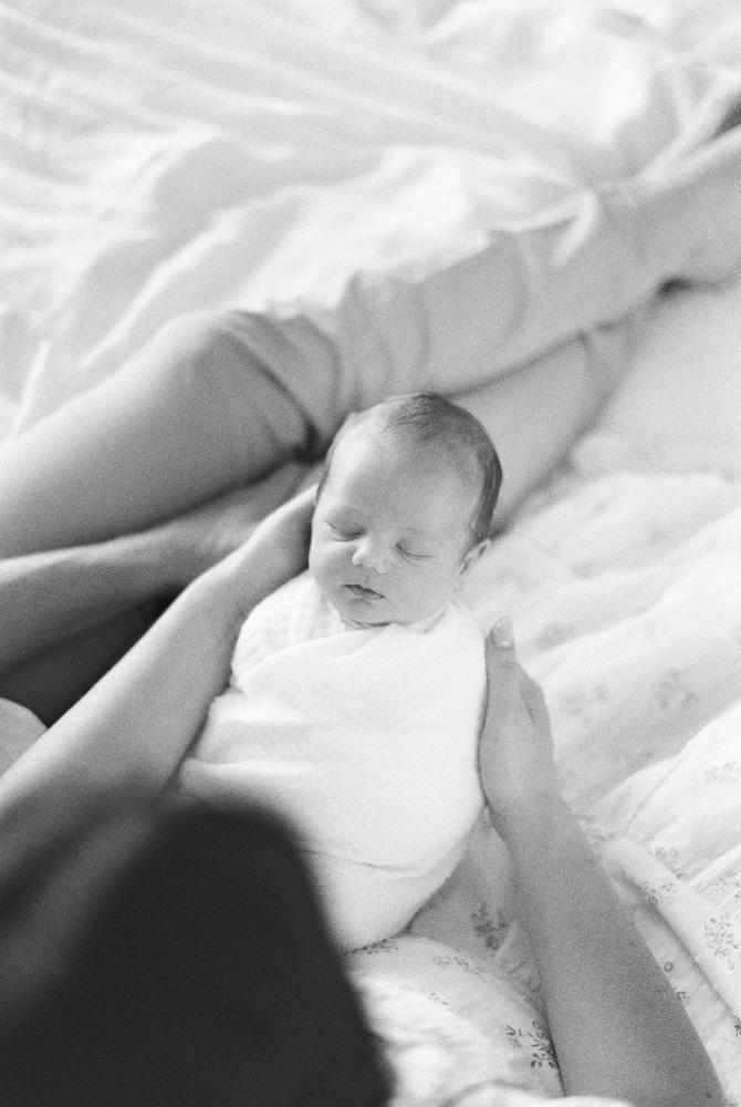 at home baby photography of newborn baby boy sleeping in mom and dad's arms