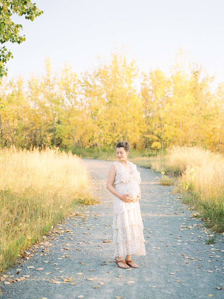 Expectant mom standing among beautiful fall trees, outdoor maternity session as one of the fun fall activities in Edmonton