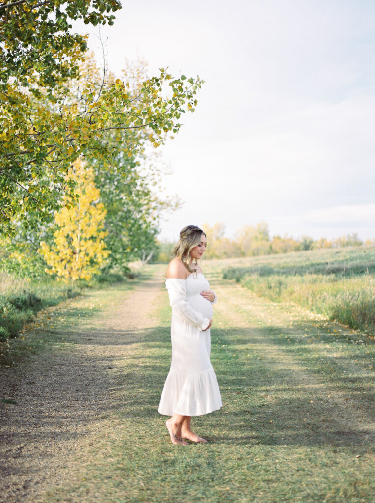 Expectant mom, cradling her bump in a beautiful field in Edmonton, Alberta