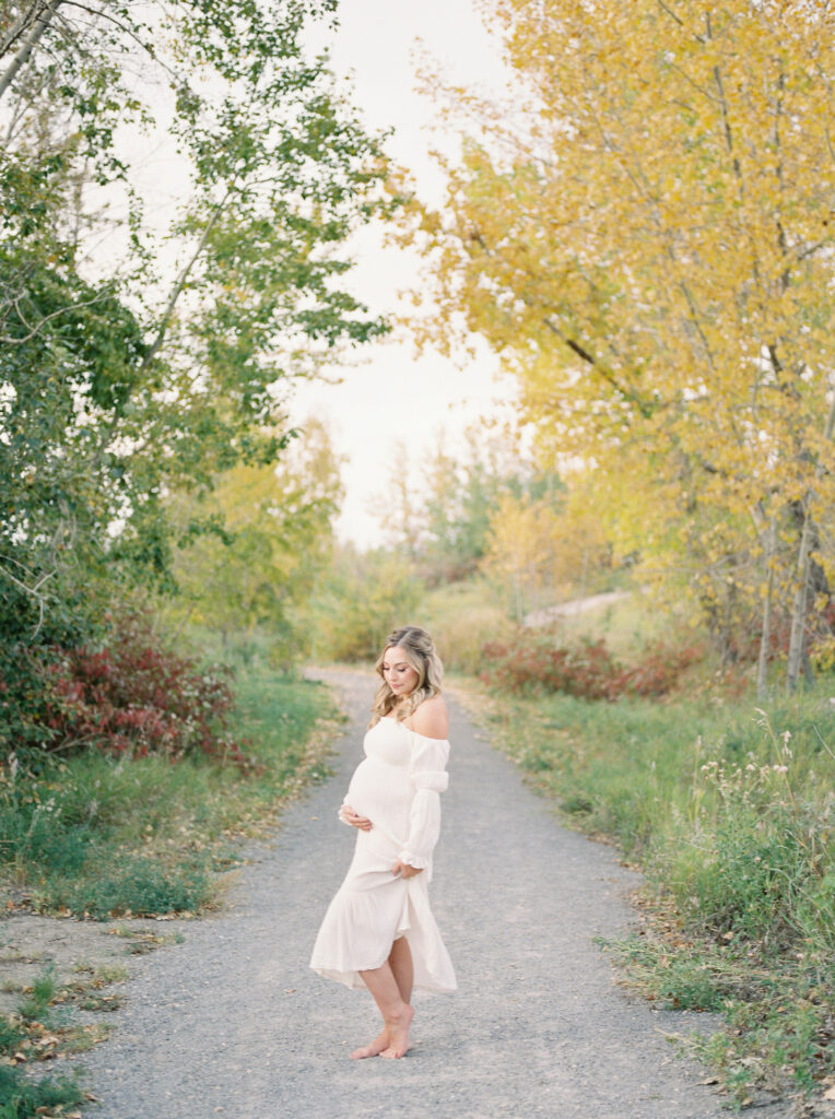 Expectant mother, standing in the beautiful fall trees in Edmonton