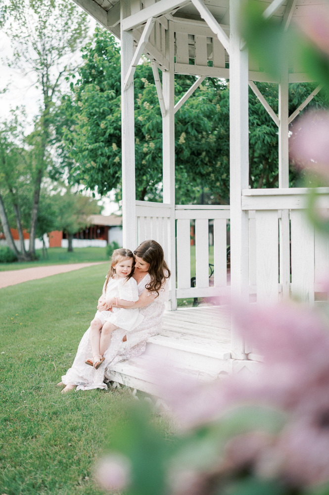 Mom and daughter snuggling together on a gazebo on a beautiful summer evening in Edmonton