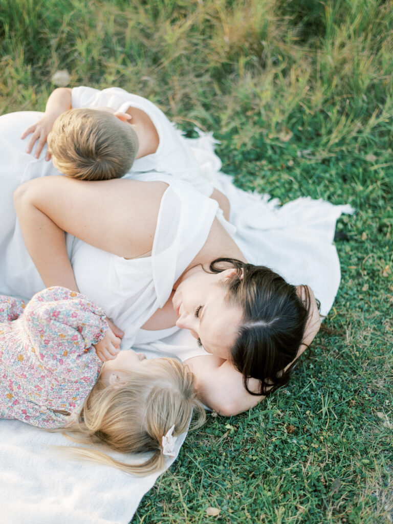 Mom snuggling with two kids in a field