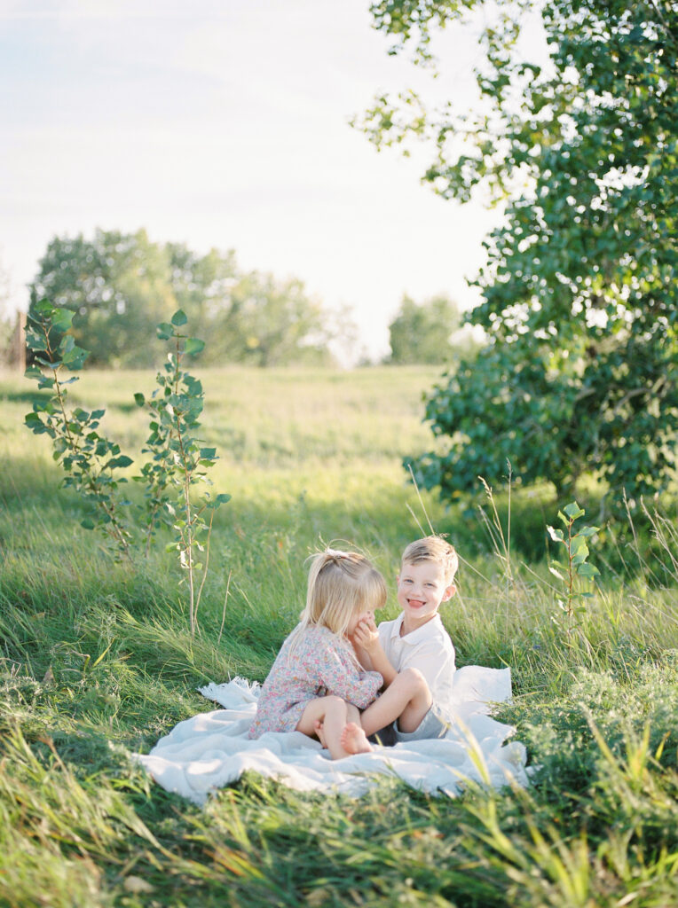 Son and daughter snuggling in the grass in a field