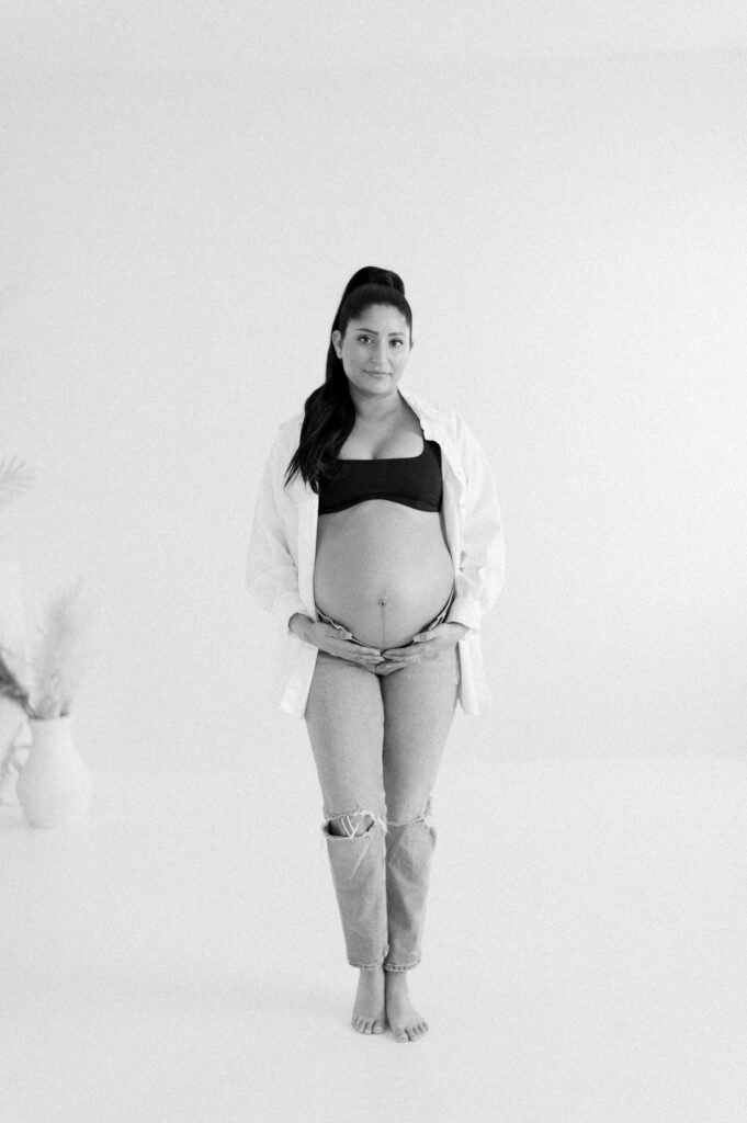 Edmonton photographer for beautiful maternity photos captures expectant mom cradling bump in studio on black and white film