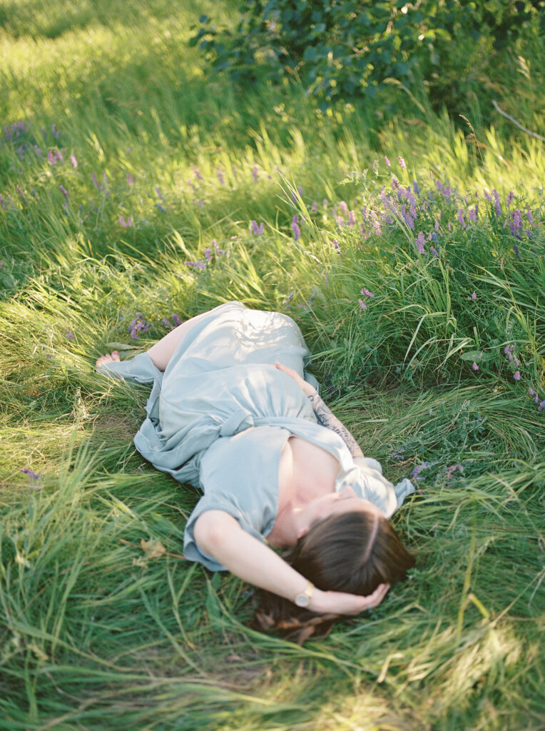 Mom laying in field of flowers, holding bump, sharing top 10 baby items for new moms