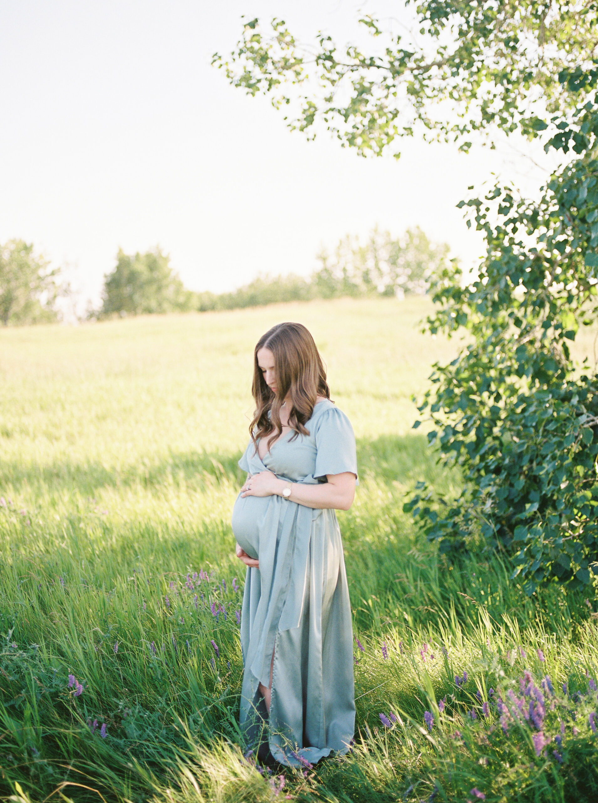 Expectant mom, hugging bump in the trees sharing top baby items for new moms