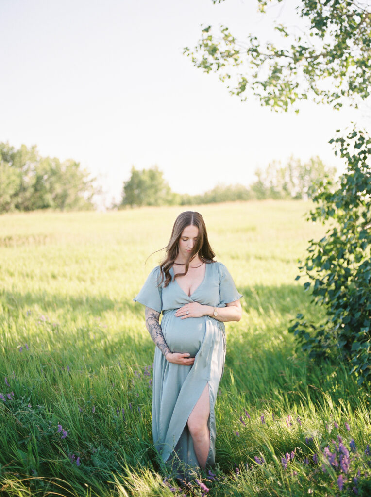 Mom standing in field of flowers, holding bump, sharing top 10 baby items for new moms