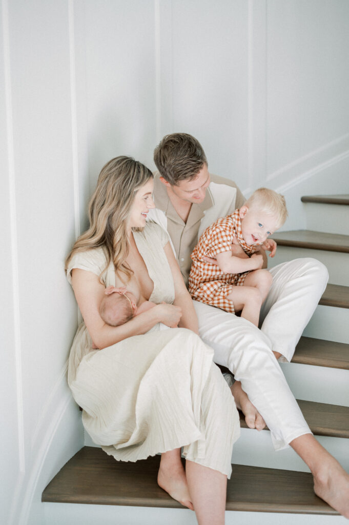 Mom, dad, toddler and baby sitting on stairs and enjoying one another's company during newborn session.