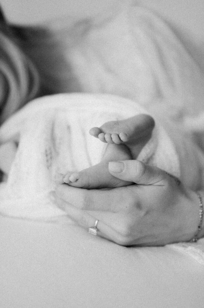 Baby foot held by adult hand, captured in black and white