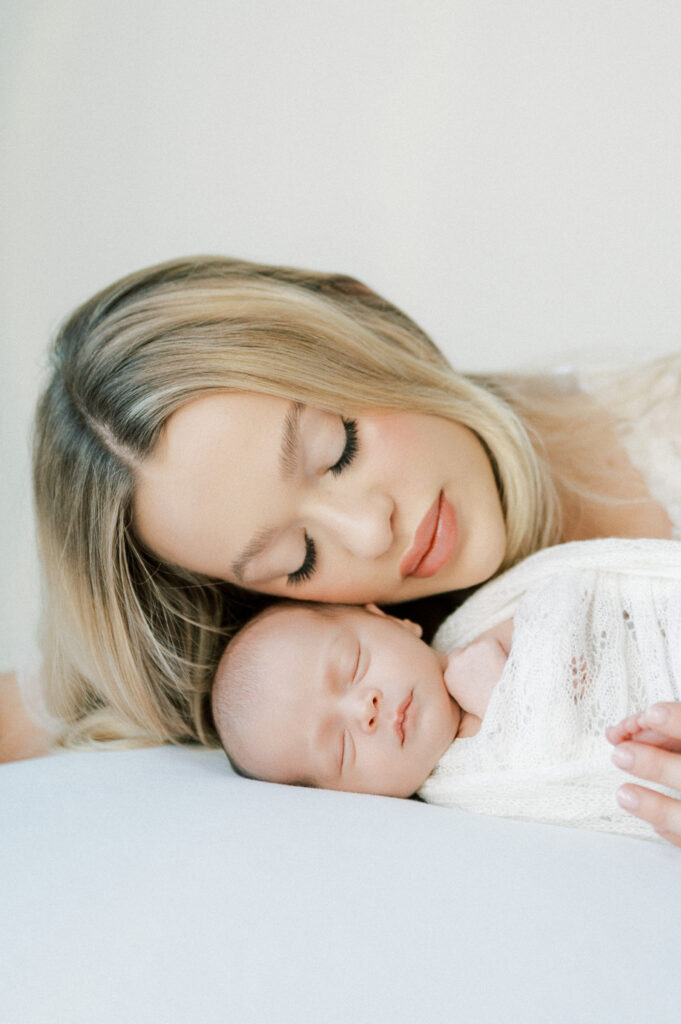 Mother and baby sharing a moment, snuggling up together during newborn photography session. 5 Must-Have Photos for Your Newborn Session.