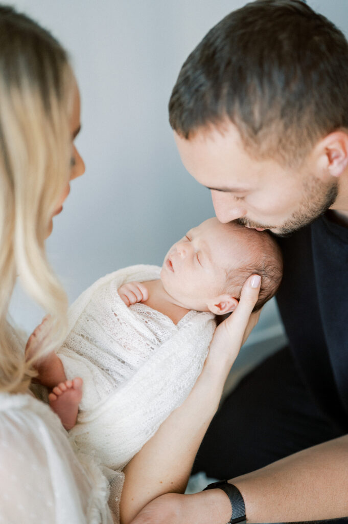 Family with newborn baby in swaddle.