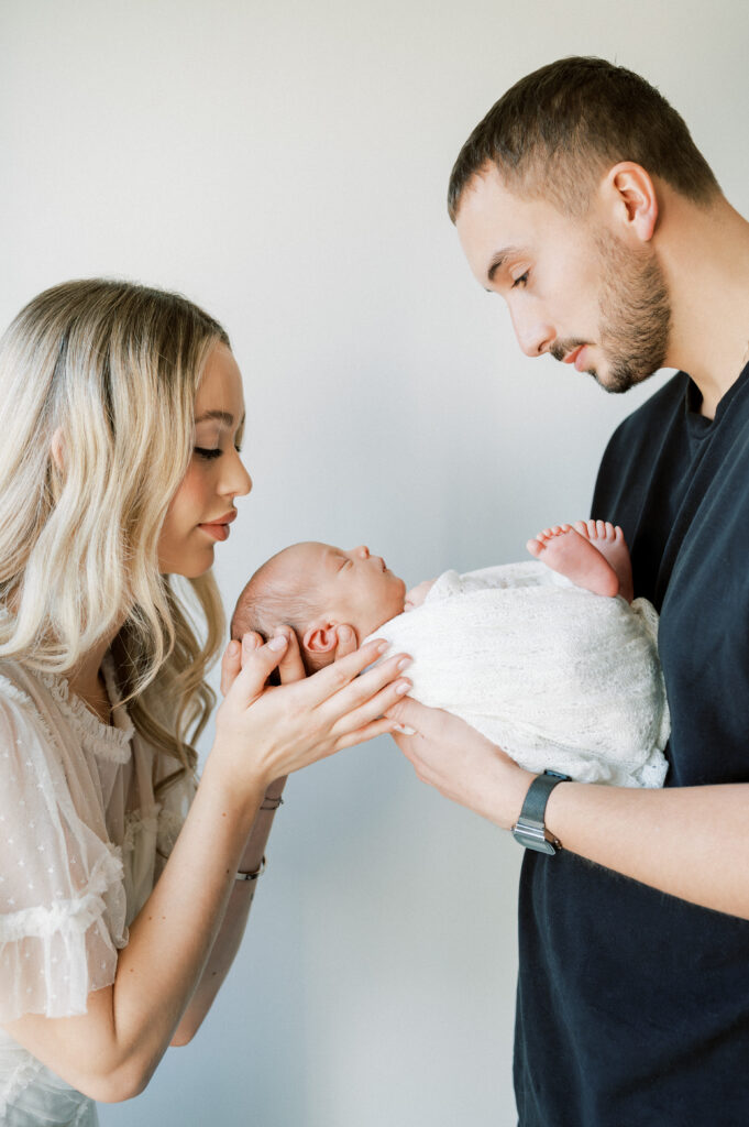 Parents holding newborn baby together.